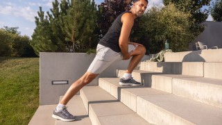 Mann in Sportkleidung macht Sportübungen an einer Treppe draußen