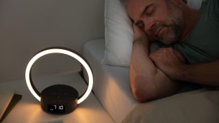 Un uomo dorme nel letto; accanto a lui, sul comodino, c'è la sveglia con luce naturale WL 65