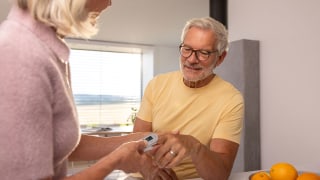 Ältere Frau misst bei einem älteren Mann zu Hause die Sauerstoffsättigung mit einem Pulsoximeter von Beurer