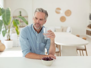 Mann sitzt am Tisch und trinkt ein Glas Wasser