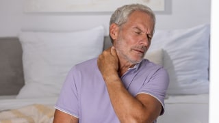 Mann hat Nackenschmerzen und fasst sich an den Nacken