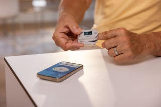 Mann nutzt PO 60 Pulsoximeter und Smartphone zur Übertragung der Werte