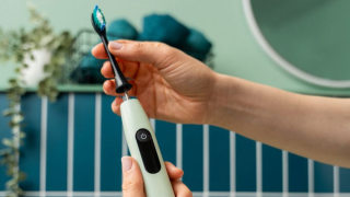 Eine Person montiert im Badezimmer einen Bürstenkopf auf die Beurer SC 50 Elektrische Zahnbürste.