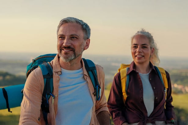 Couple âgé en randonnée sur la montagne avec vue verte sur la vallée en arrière-plan
