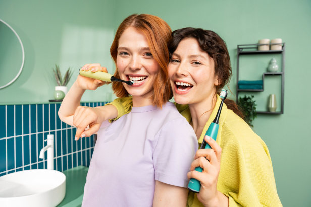 Zwei junge Frauen in einem modernen Badezimmer haben die SC 50 in Splashy Lemon und Ocean Breeze in der Hand und strahlen