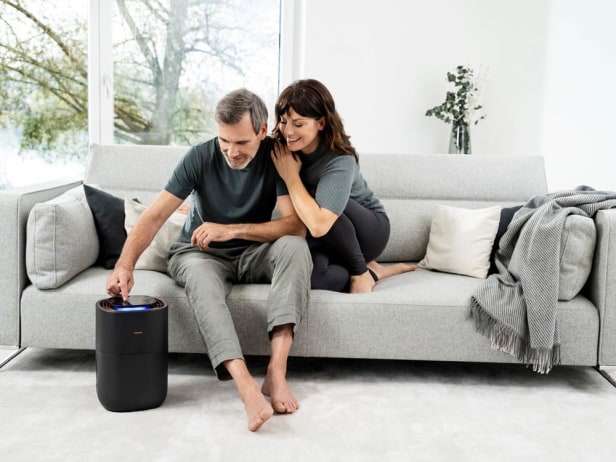 Un homme utilise le purificateur d'air LB 300 Un couple est assis ensemble sur le canapé et l'homme utilise l'humidificateur LB 300.