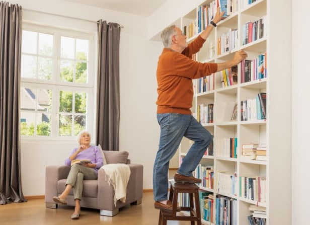 Ältere Personen im Wohnzimmer am Bücherregal Ältere Personen im Wohnzimmer am Bücherregal