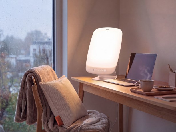 La lampe à lumière du jour TL 95 de Beurer dans le bureau à domicile La lampe à lumière du jour TL 95 se trouve sur le bureau de mon bureau à domicile, avec un ordinateur portable et une tasse de café bien chaud à côté.