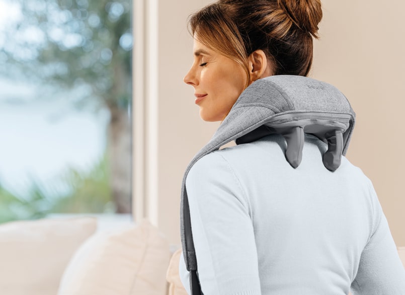 Donna che ha posizionato il massaggiatore sulle spalle