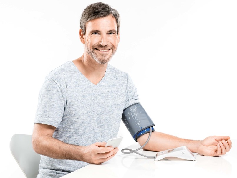 Un homme mesure sa tension artérielle et vérifie les valeurs mesurées sur son smartphone