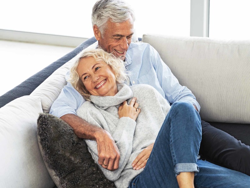 Une femme et un homme se câlinent bras dessus bras dessous sur le canapé