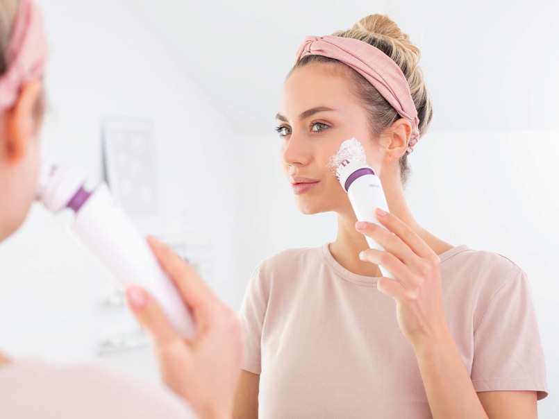 Une femme se nettoie le visage avec le Beurer FC 95