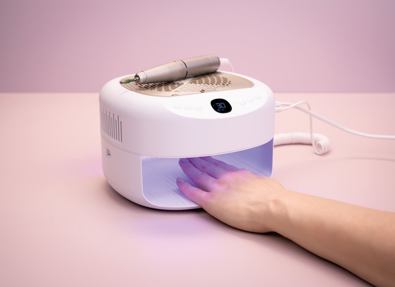 Mano distesa nella lampada UV di una macchina per manicure