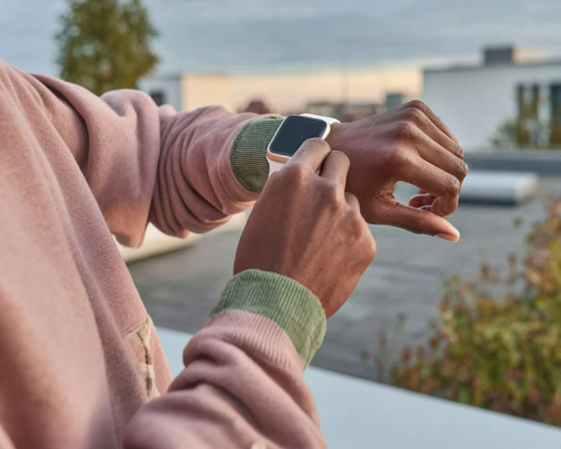 Mann steht auf Balkon und schaut auf seine Apple Watch