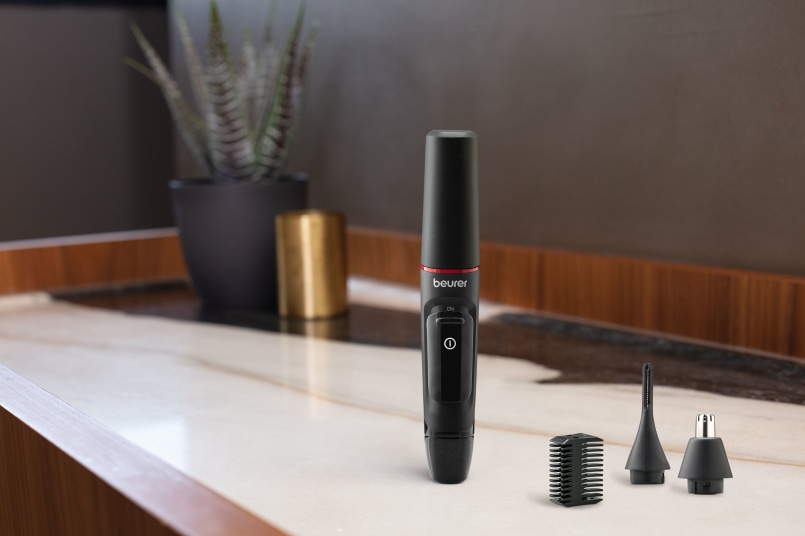 Beurer MN3X Präzisionstrimmer steht im Badezimmer und daneben liegen die mitgelieferten Aufsätze