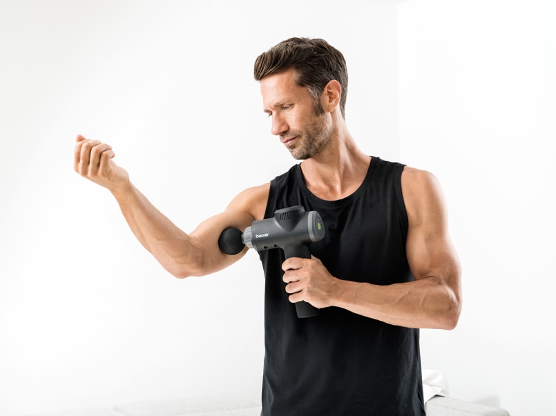 Mann wendet MG 180 Massagepistole am Oberarm an