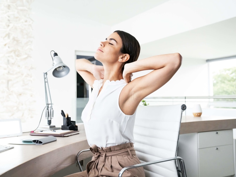 Frau streckt sich am Arbeitsplatz