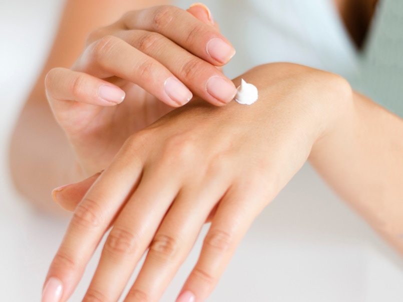 Nahaufnahme zweier Hände, wobei eine Hand eine kleine Menge Creme auf den Handrücken der anderen aufträgt.