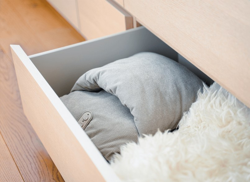 Beurer FM 28 Fußmassagekissen in Hellgrau verstaut in einer Schrankschublade zusammen mit einem weißen Fell