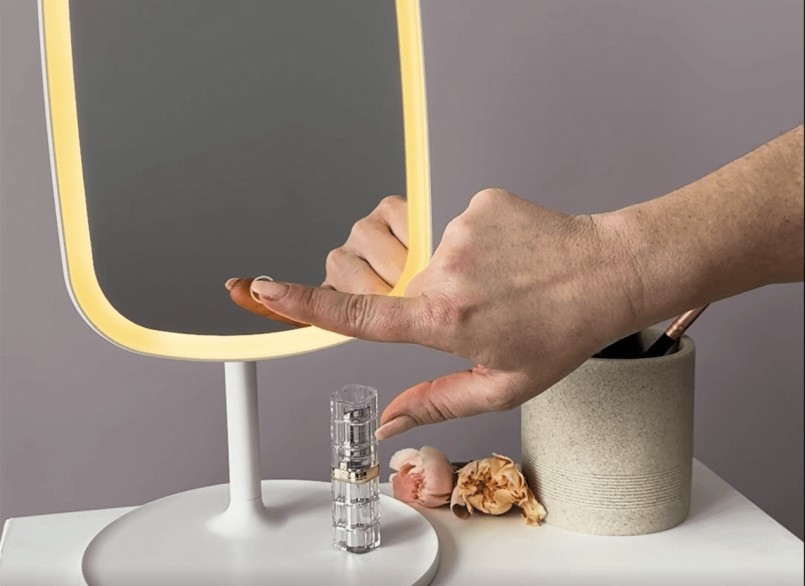 Eine Hand betätigt den beleuchteten Kosmetikspiegel BS 47 von Beurer mittels Berührung.