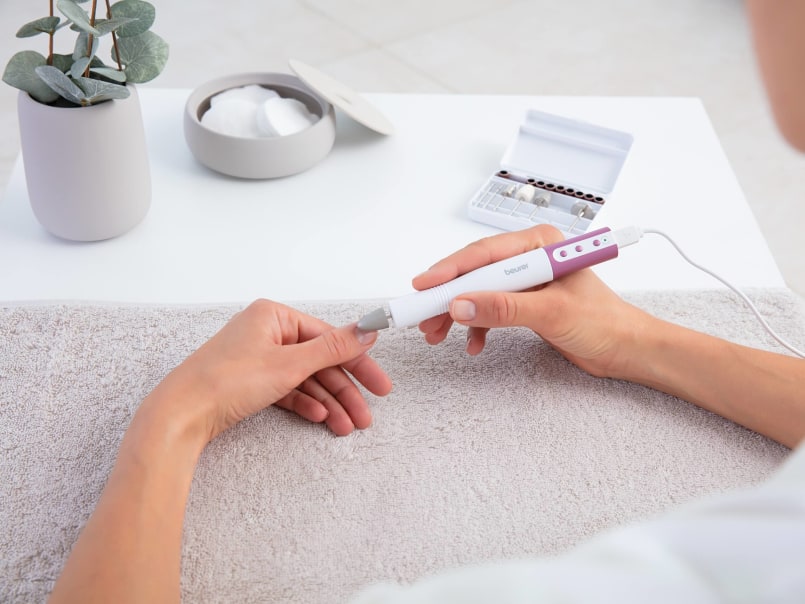 Person hält Maniküre-/Pediküreset MP 52 und bearbeitet Fingernagel, im Hintergrund sind Zubehörteile und Dose mit Wattepads.