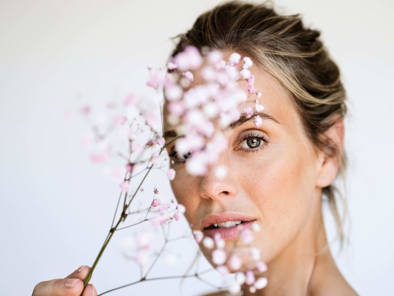 Frau hält sich Blume vors Gesicht