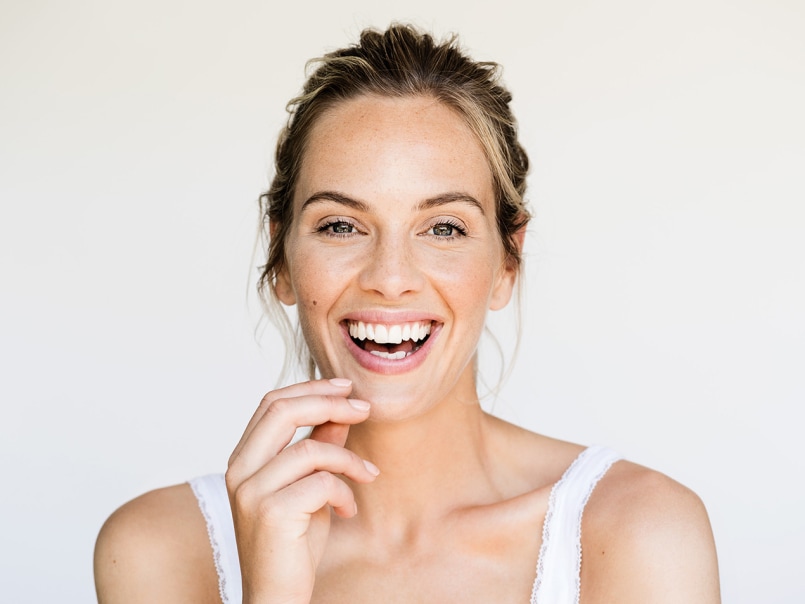 Frau lacht herzlich und hat ihre Hand am Kinn