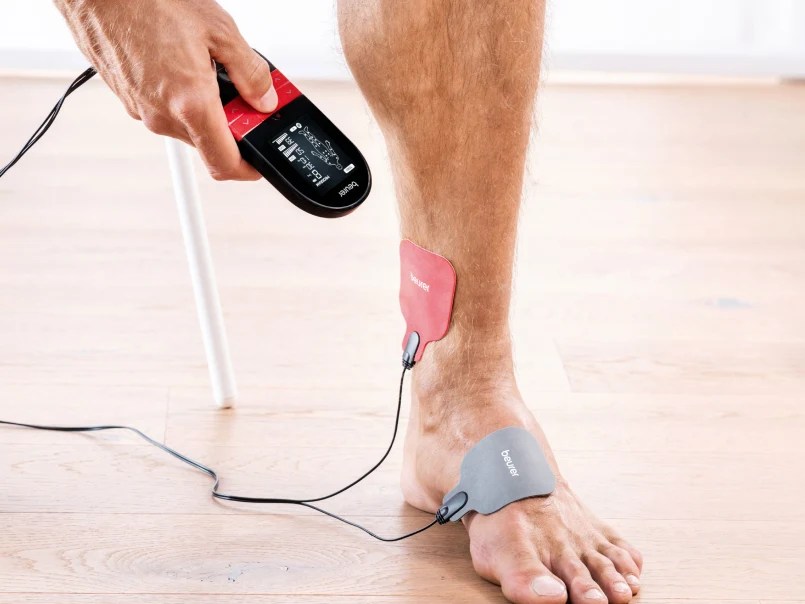 Es ist ein Fuß zu sehen, an den Elektroden befestigt sind und das tens gerät.