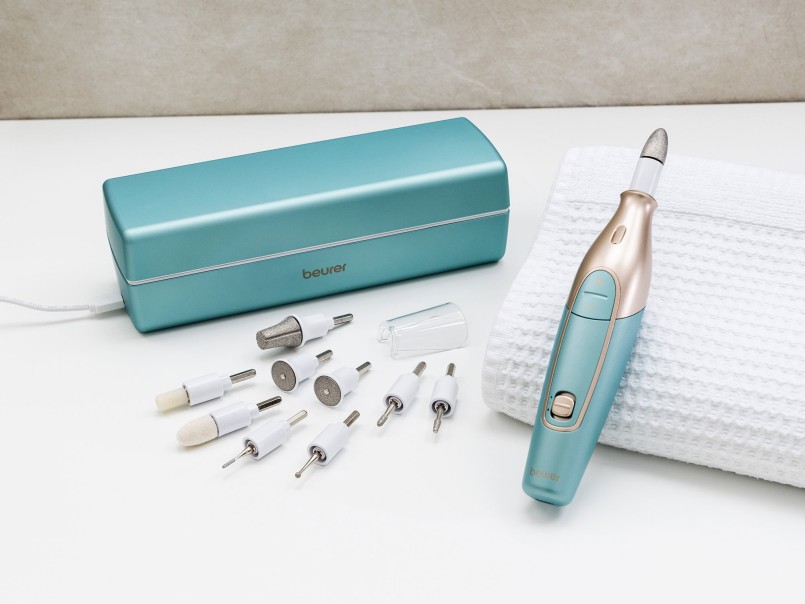Beurer MP 84 in mint platziert auf einem Handtuch, daneben die aufgereihten Aufsätze und die Ladebox, angeschlossen an das Ladekabel