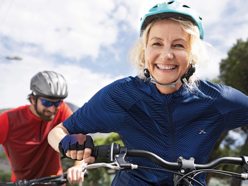Zwei Radfahrer mit Helmen fahren bei Sonnenschein und tragen Sportkleidung.