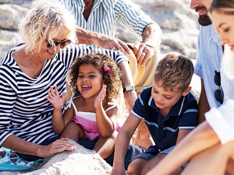 Mehrere Personen unterschiedlichen Alters sitzen gemeinsam am Strand