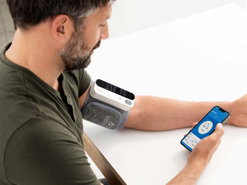 Mann hält Smartphone in der Hand und misst seinen Blutdruck