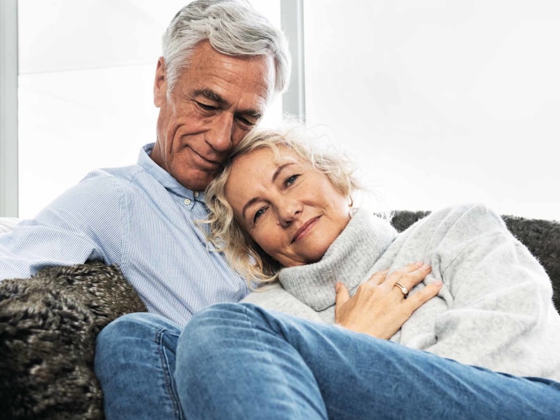 Frau und Mann liegen Arm in Arm auf dem Sofa und kuscheln