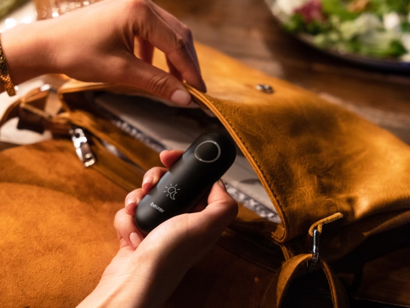 Der Insektenstichheiler von Beurer wird in einer Tasche, die auf dem Tisch liegt, verstaut