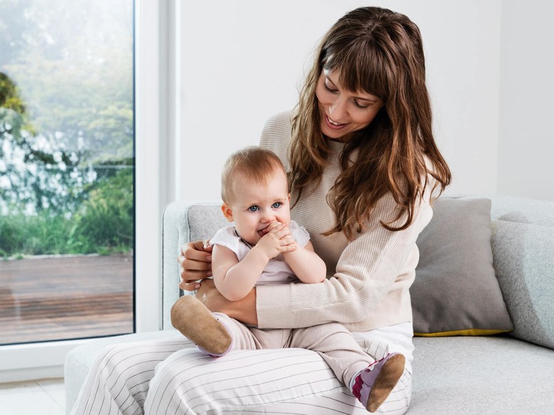 Mutter sieht auf ihr Baby hinab, das in auf ihrem Schoß in ihrem Arm sitzt