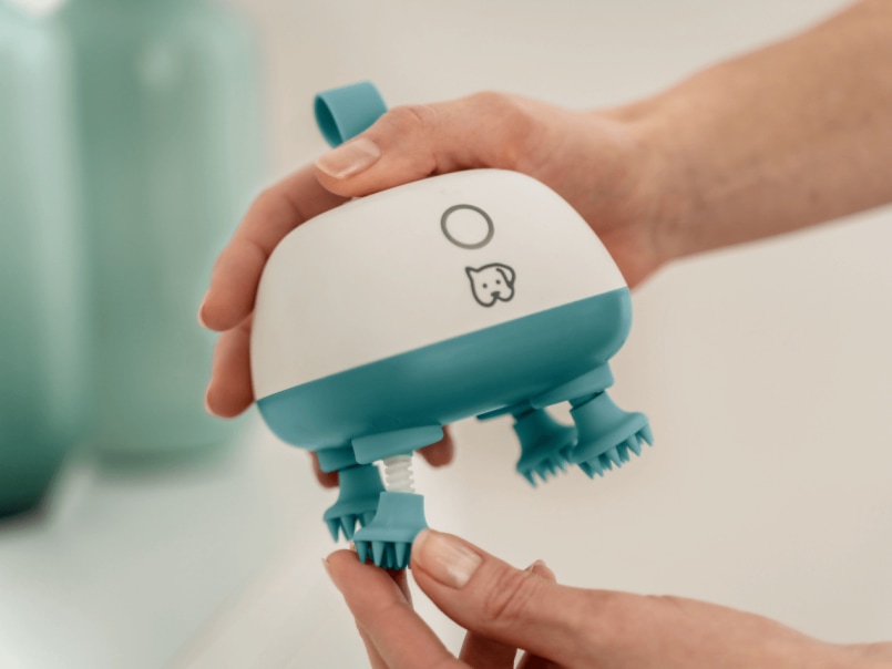 Das Massagegerät Buddy wird in der Hand gehalten und ein Massagekopf wird abgedreht