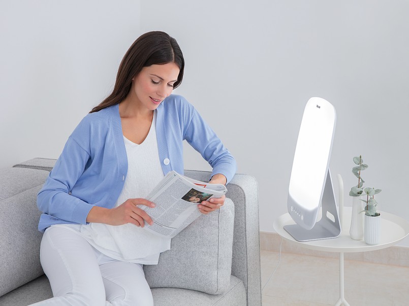 Junge Frau, die auf einem grauen Sofa sitzt und von der TL 95 angestrahlt wird.