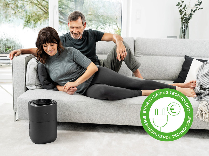 Ein Mann und eine Frau liegen auf einem modernen Sofa und schauen auf den LB 200. 