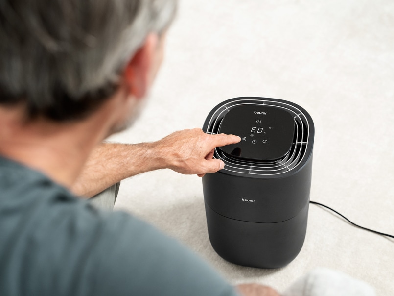 Ein älterer Mann ist mit den Oberkörper dem LB 200 zugewandt und berührt ihn mit seinem Finger.