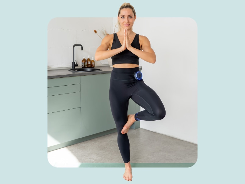 2 Frauen stehen auf Yoga Matte und führen im Stehen ein Stretch Übung aus