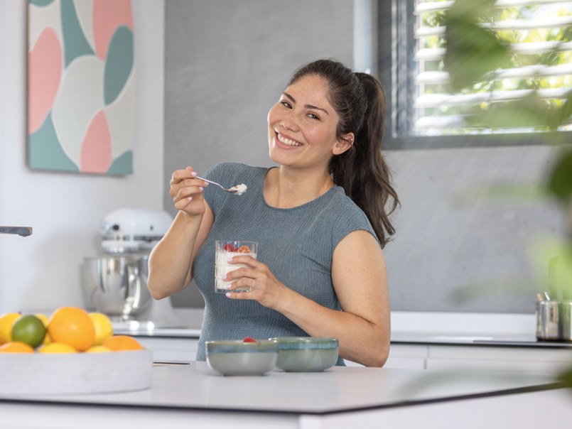 Frau isst Joghurt in einer modernen Küche