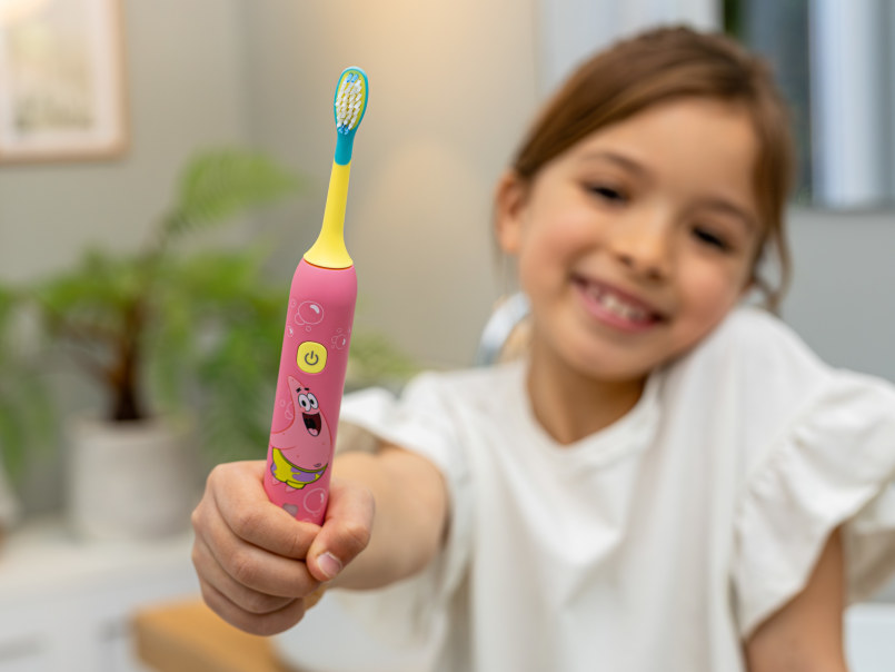 Junges, dunkelhaariges Mädchen lächelt und hält die SC 11 in Seastar Pink vor sich hoch