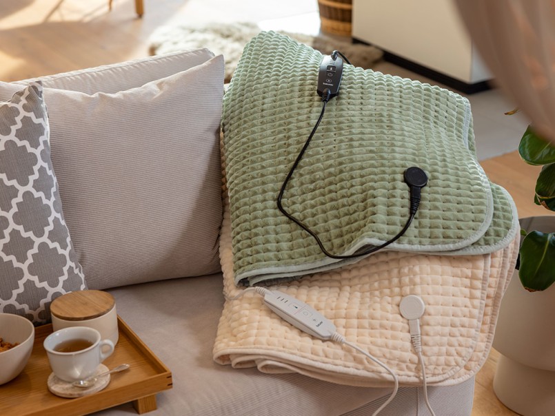 Beurer HD 72 Waffle elektrische bovendekens in Sage Green en Cream op de bank