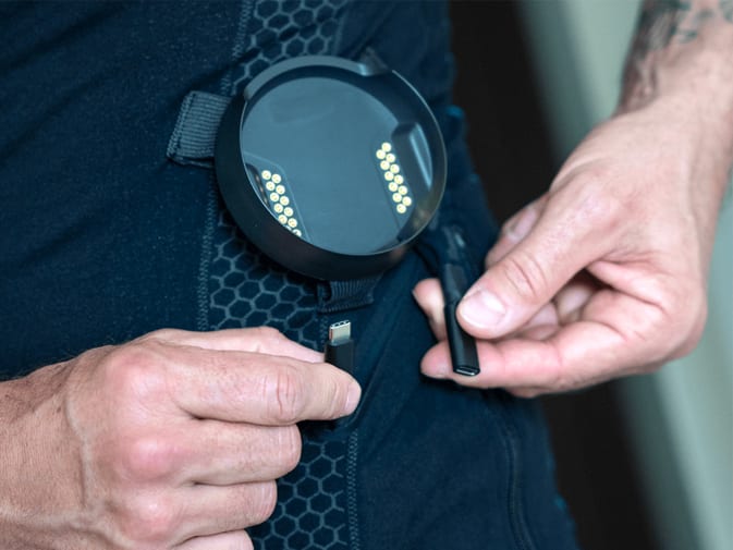 Une personne relie le maillot Antelope EMS à la partie inférieure Antelope EMS par un câble intégré.