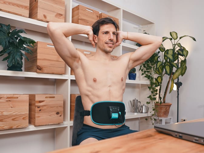 A man trains at home with the Corefit EMS belt from Antelope.