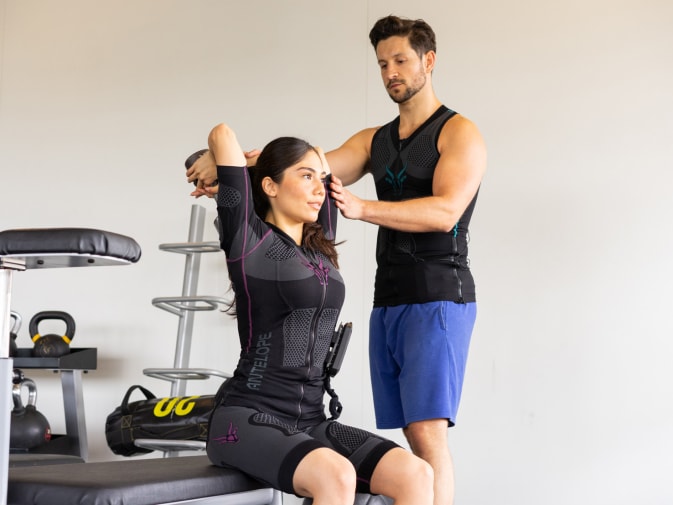 Eine Frau führt ein Rücken Training mit einem EMS Personal Trainer zum Muskelaufbau durch.