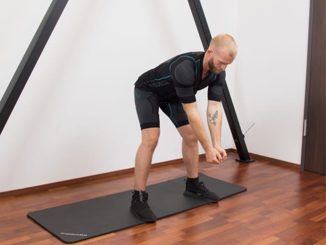 A man performs deadlifts in the Antelope EMS suit in his home.