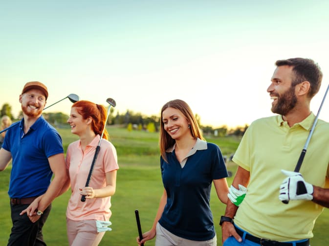 Vier Personen haben Spaß beim Golf-Training auf einem Golfplatz.