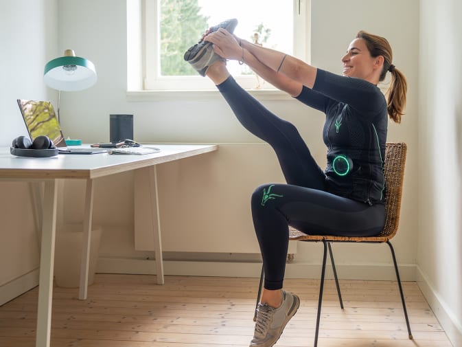 Eine Frau macht ein Pause vom EMS Training mit dem EMS Anzug und der Antelope Go App.