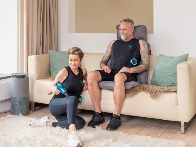 Eine Frau und ein Mann regenerieren mit den EMS Anzügen von Antelope und den Massage Produkten von Beurer.